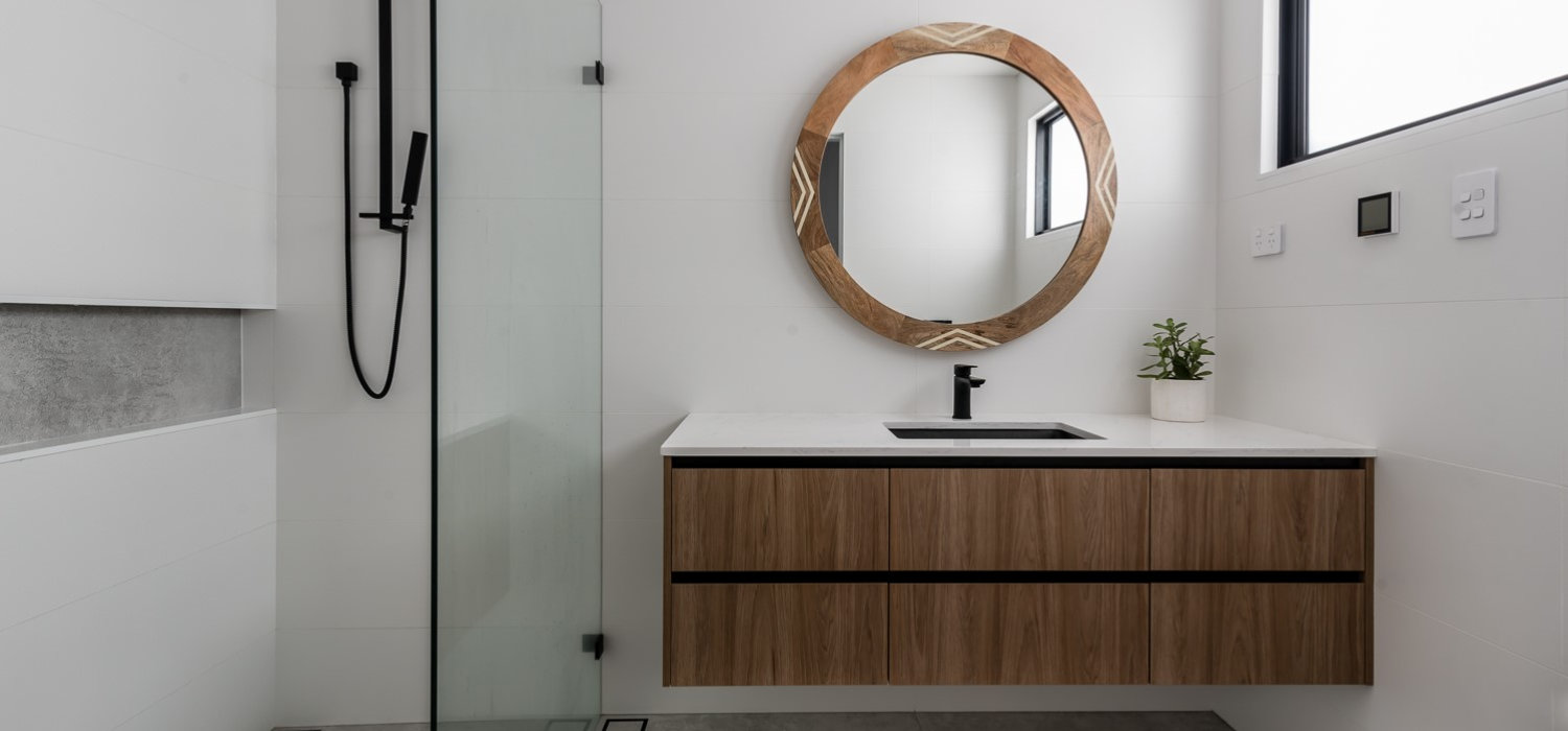 Timber-look bathroom vanity with drawers beneath a round mirror